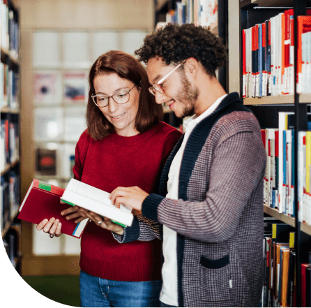 Two people reading books in a University library.